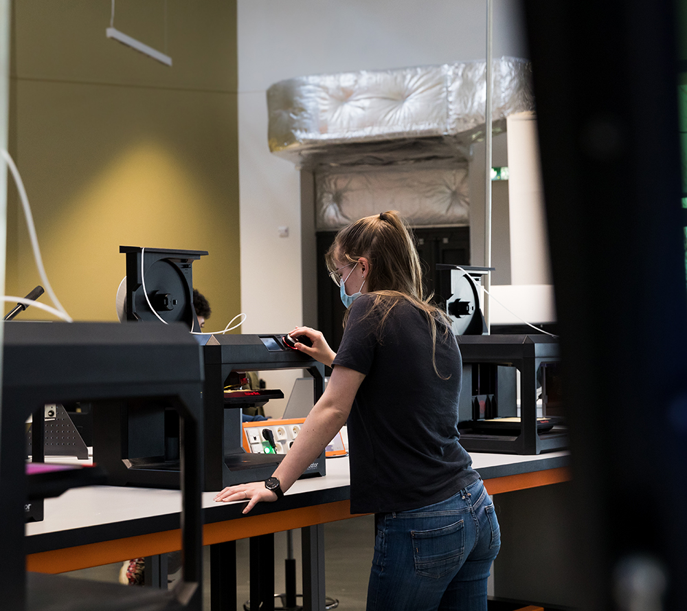 apprentie (femme) manipulant une imprimante 3d à filament au FabLab de Hall 32