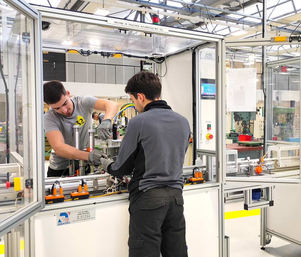 Apprenants en Bac Pro PLP en train de manipuler une machine de ligne de production sur le plateau technique